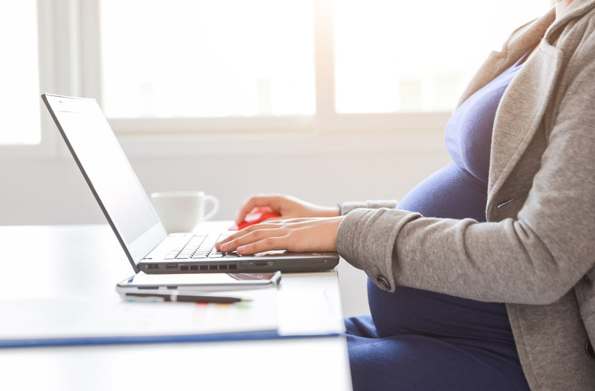 Schwangere Frau arbeitet an Computer