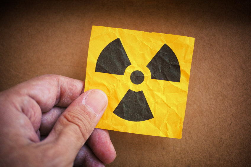 Männerhand hält einen Zettel mit Warnung vor Radioaktivität
